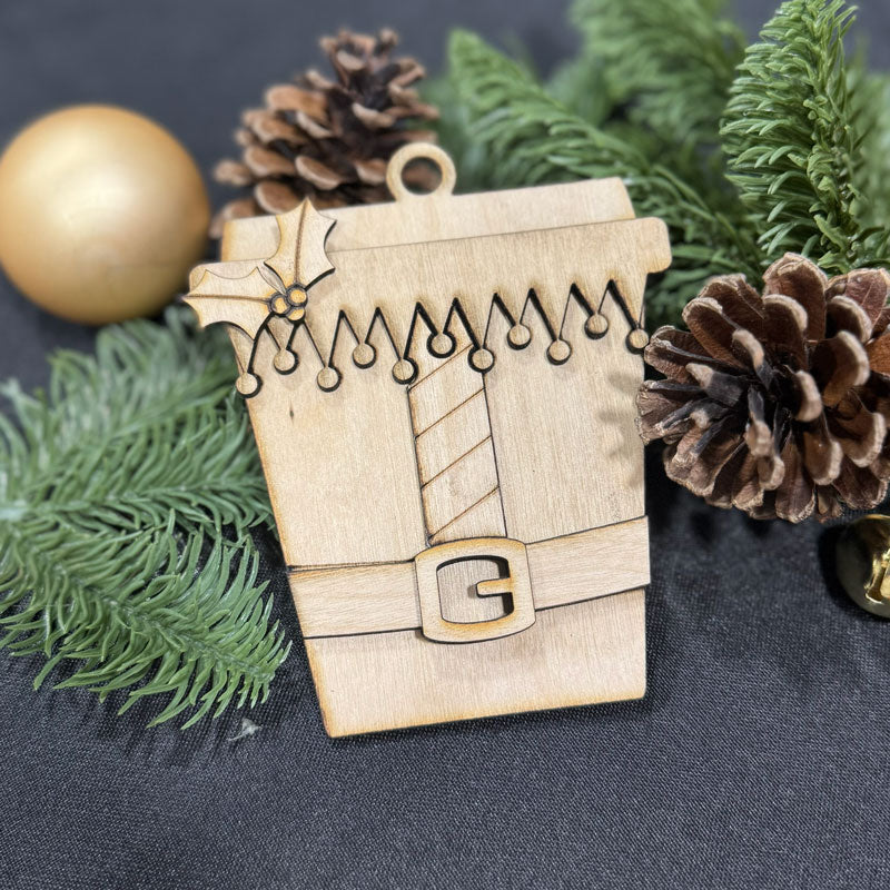 Wooden ornament shaped like a coffee cup with Christmas decorations on a dark background