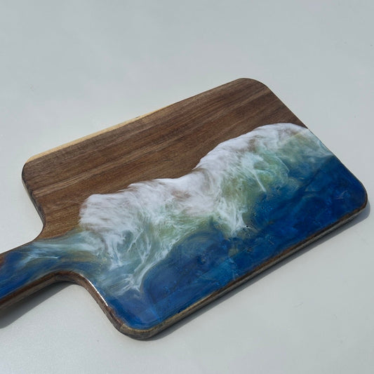 Wooden cutting board with ocean design on a white surface
