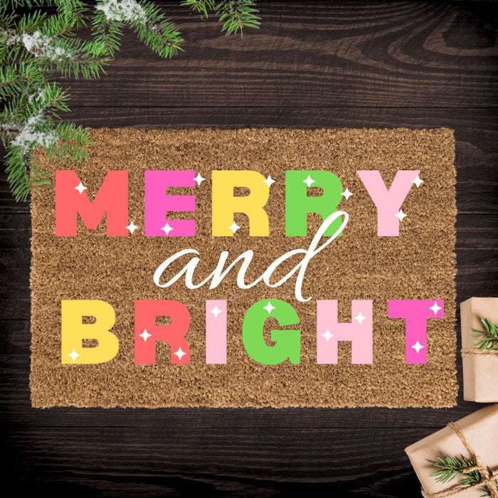 Doormat with 'Merry and Bright' text on a wooden floor with Christmas decorations.