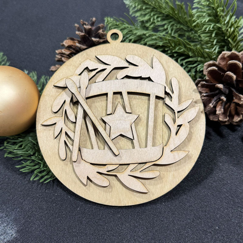 Wooden Christmas ornament with star and branch design on a dark fabric background with pine cones and an egg.