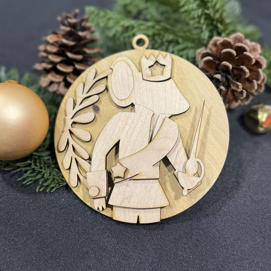 Wooden ornament with a design of a person holding a crown and staff, surrounded by pine cones and greenery on a dark background.