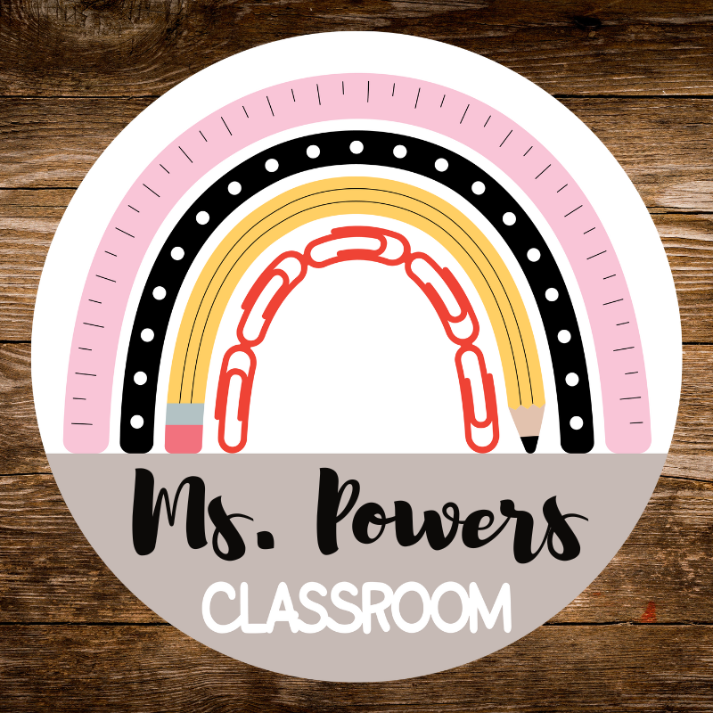 Circular sign with rainbow design and text 'Ms. Powers Classroom' on a wooden background