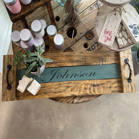 Wooden tray with personalized name 'Johnson', candles, and decorative items on a wooden surface.