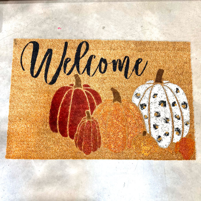 Doormat with pumpkins and 'Welcome' text on a textured surface