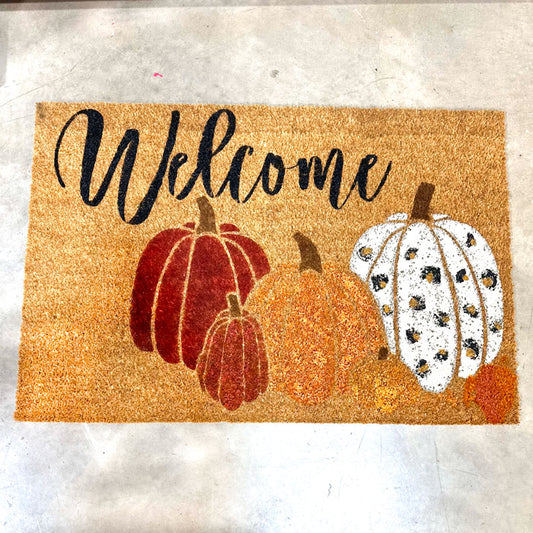 Doormat with pumpkins and 'Welcome' text on a textured surface