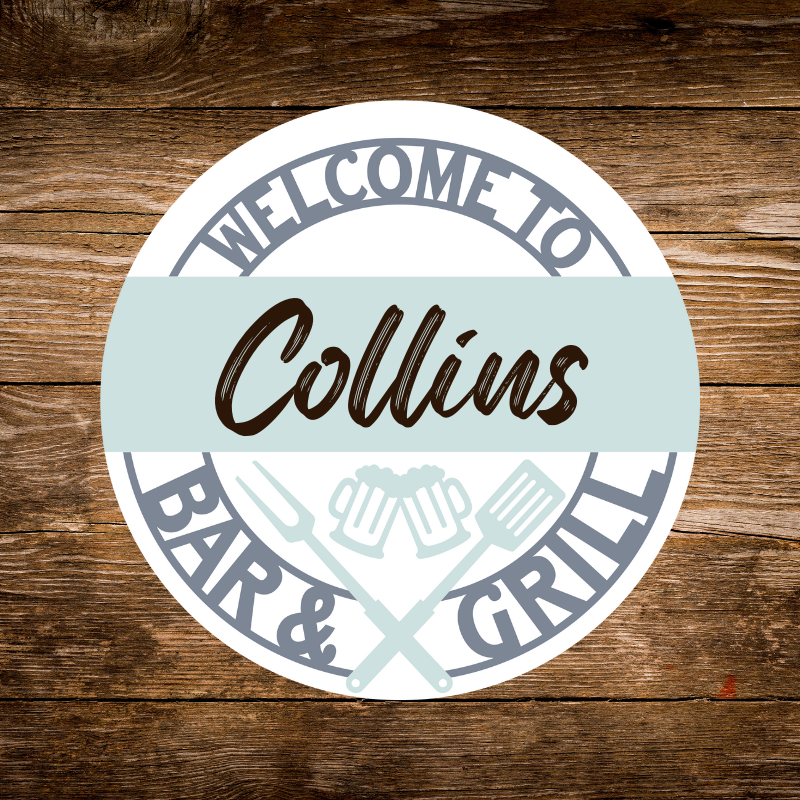Round sign with 'Welcome to Collins Bar & Grill' text on a wooden background