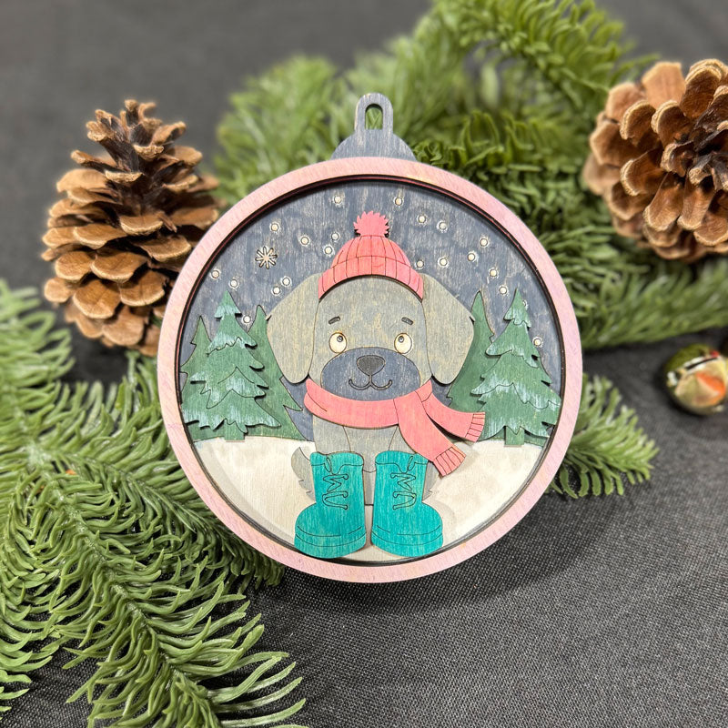 Decorative Christmas ornament with a dog wearing winter clothing, surrounded by pine cones and branches.