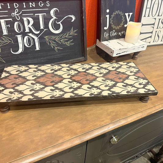 Decorative tray with pattern on a wooden surface with festive signs in the background.