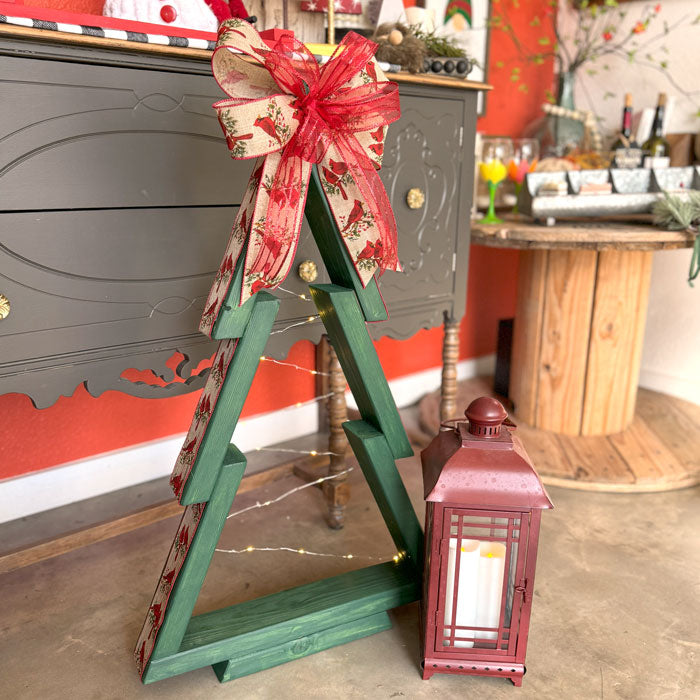 Decorative green wooden tree with a red bow in a festive indoor setting