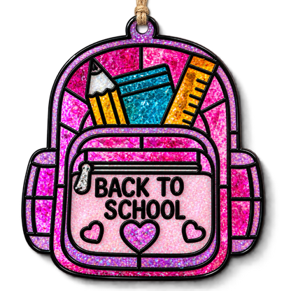 A decorative hanging suncatcher shaped like a pink glittery backpack with black outlines and school supplies peeking out, including a pencil, notebook, and ruler. The front pocket reads “BACK TO SCHOOL” with small heart details, suspended by a tan string on a white background.