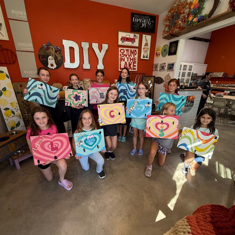 Children holding up their handmade crafts at The DIY District 