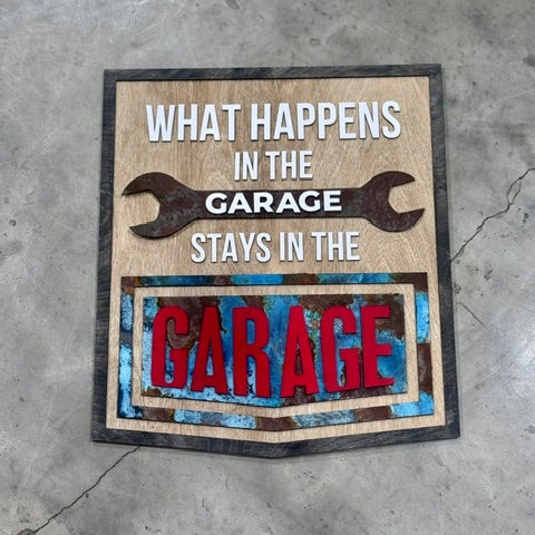 Decorative sign with text 'What happens in the garage stays in the garage' on a concrete floor.