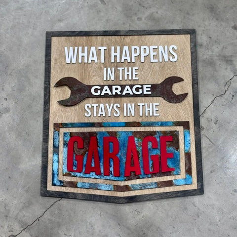 Decorative sign with text 'What happens in the garage stays in the garage' on a concrete floor.