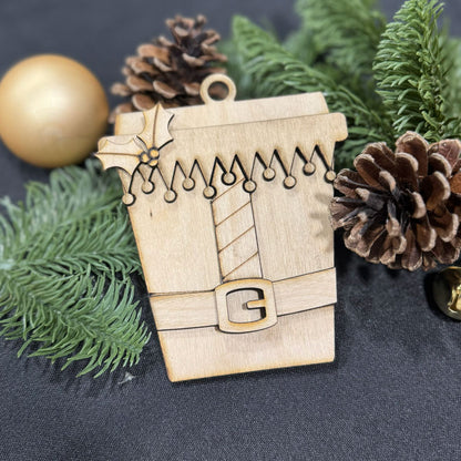 Wooden ornament shaped like a coffee cup with Christmas decorations on a dark background