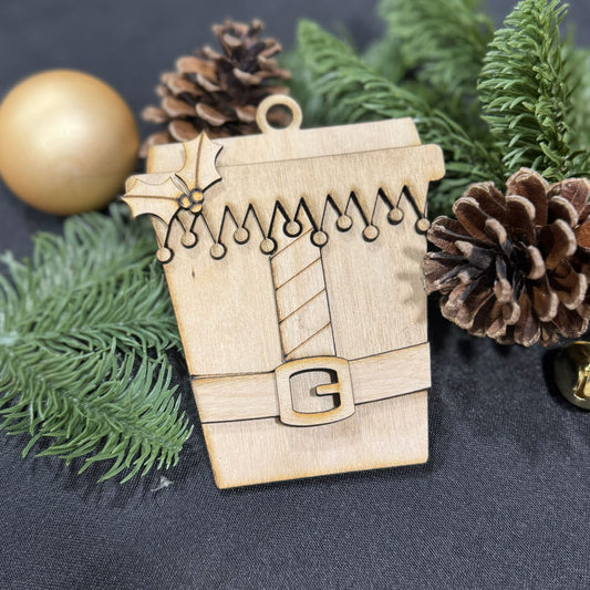 Wooden ornament shaped like a coffee cup with Christmas decorations on a dark background
