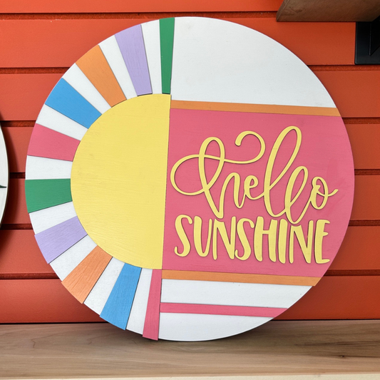 Decorative circular sign with 'Hello Sunshine' text on a wooden surface