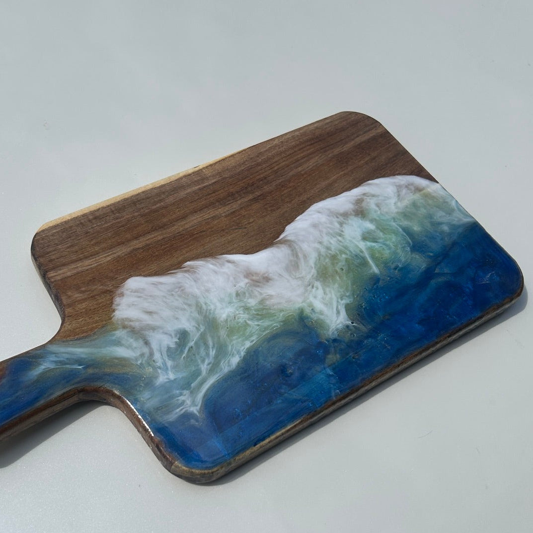 Wooden cutting board with ocean design on a white surface