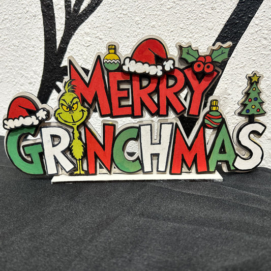 Decorative sign with 'Merry Grinchmas' text and Grinch character on a textured surface.