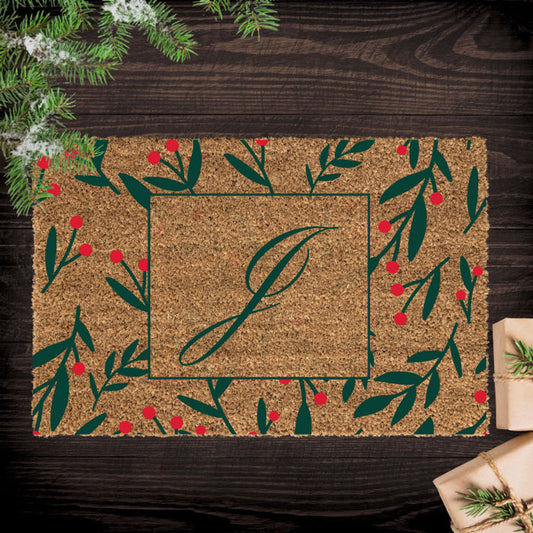 Decorative doormat with a monogram on a wooden surface with Christmas decorations.