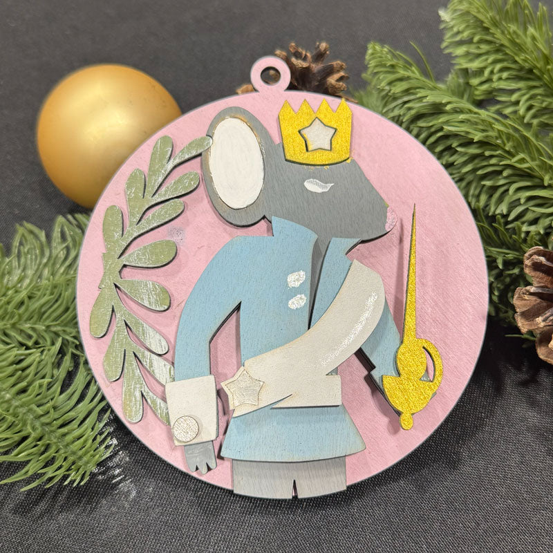 Decorative Christmas ornament with a king figure on a pink background, surrounded by greenery and a gold ball.
