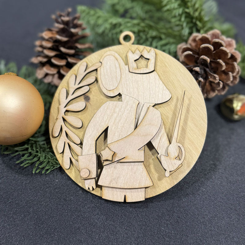 Wooden ornament with a design of a person holding a crown and staff, surrounded by pine cones and greenery on a dark background.
