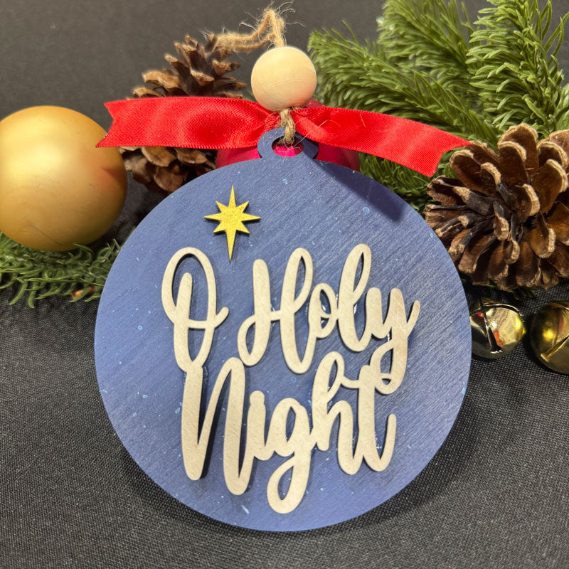 Christmas ornament with 'O Holy Night' text on a blue background, surrounded by festive decorations.