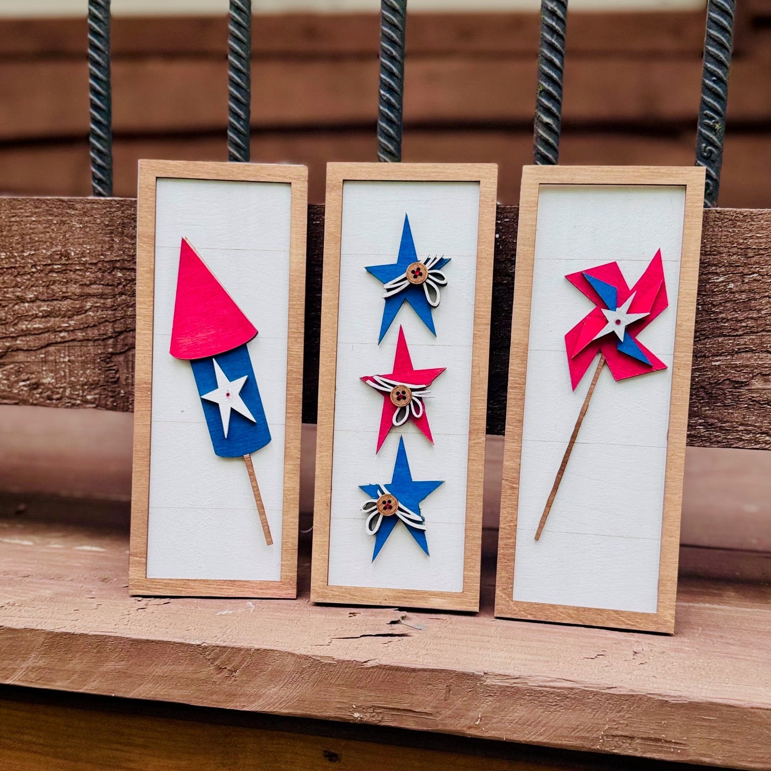 Three wooden frames with colorful windmill designs on a wooden surface.