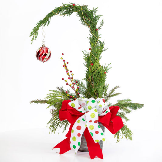 Decorative Christmas arrangement with greenery, red berries, and a polka dot ribbon on a white background