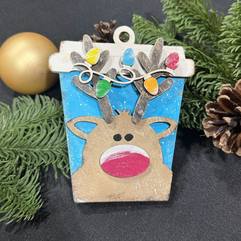 Decorative reindeer ornament with colorful lights on a dark background with greenery.