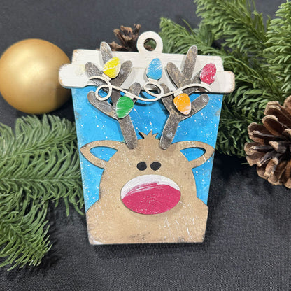 Decorative reindeer ornament with colorful lights on a dark background with greenery.