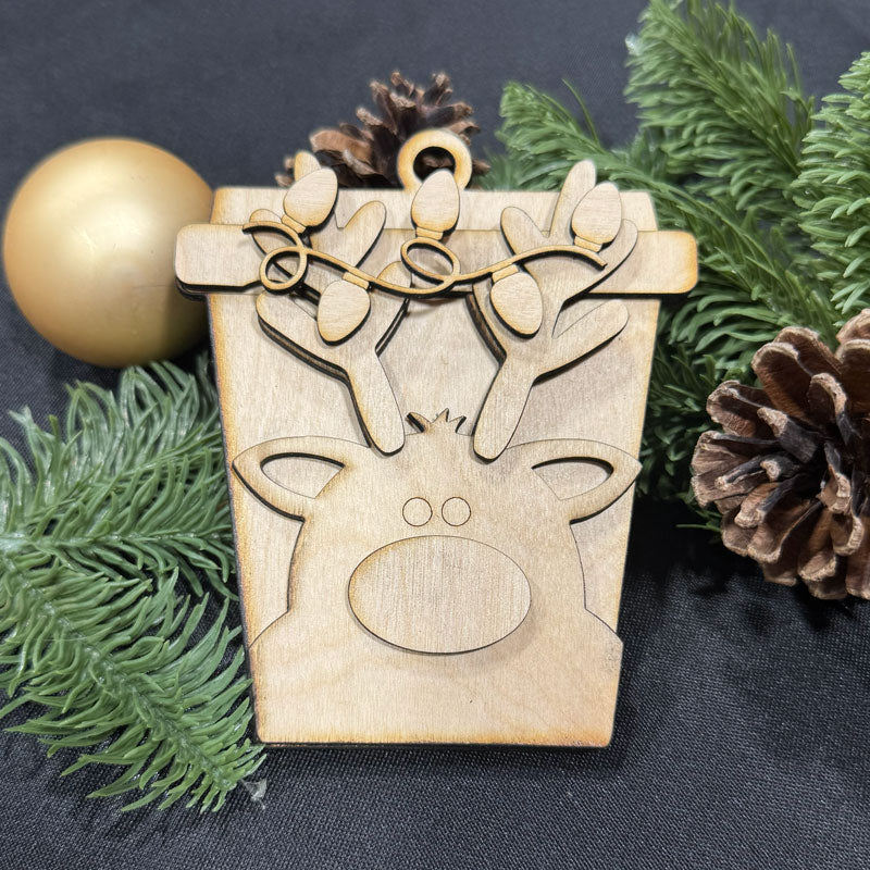 Wooden reindeer ornament on a dark background with greenery and pine cones.