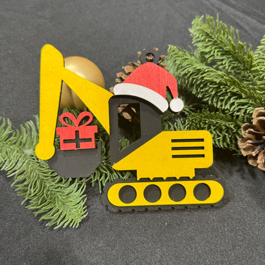 Decorative excavator ornament with a Santa hat and gift on greenery