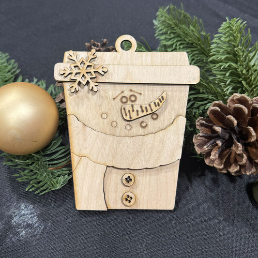 Wooden snowman ornament with a snowflake on top, surrounded by greenery and a gold ball.