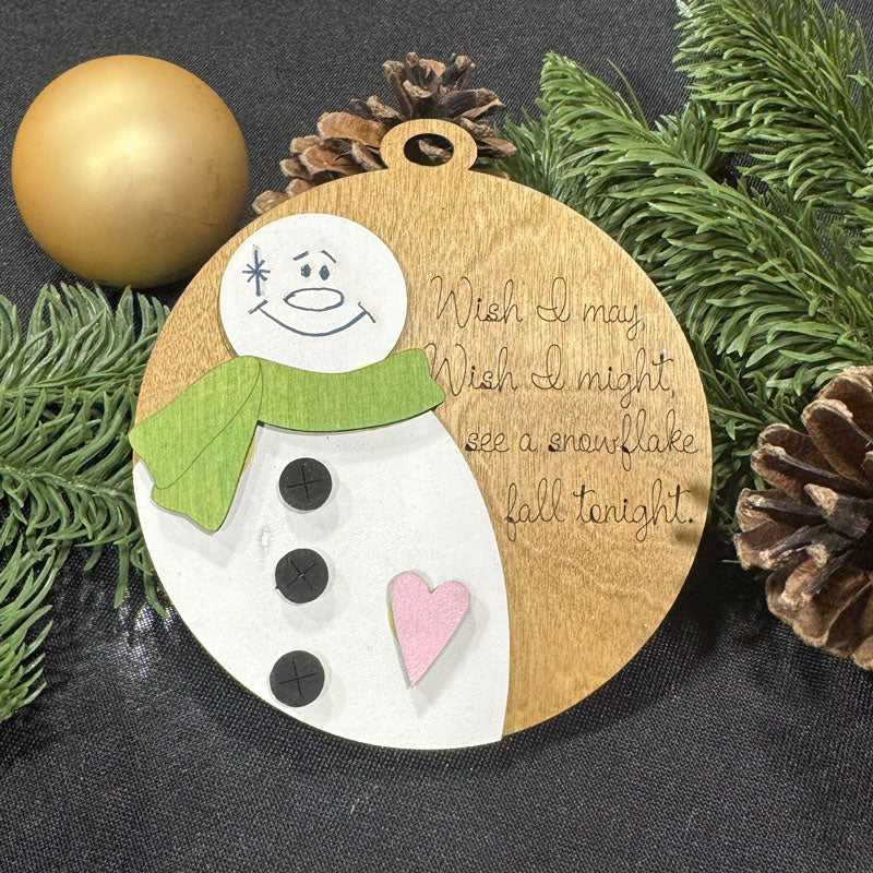 Wooden ornament with snowman design and Christmas elements on a dark background