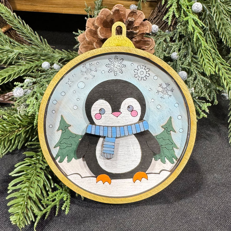Decorative penguin ornament with a gold frame surrounded by greenery
