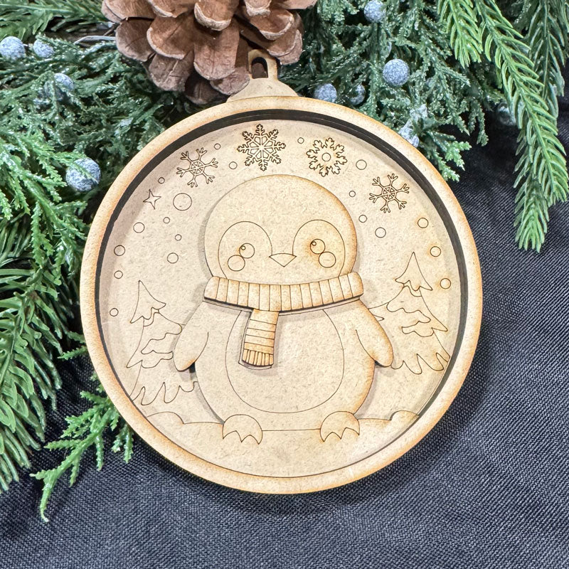 Wooden ornament with a penguin design on a dark fabric background with greenery.